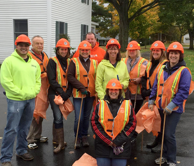 A team of NYCM Insurance employees volunteering in 2017, wearing hard-hats and vests.